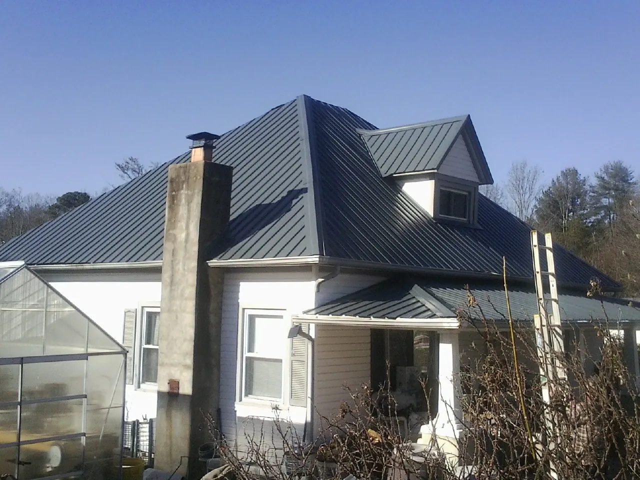 Dark blue standing seam metal roof on a white farmhouse with dormer — Slate & Tile Roof Repair by Roofing Brothers in Santo Domingo Pueblo