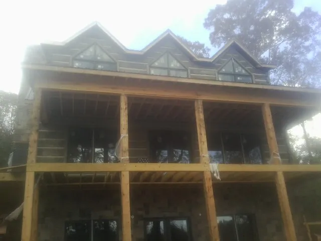Dormers and porch framing on a large log home under construction — Roof Coating work by our crew in Santo Domingo Pueblo