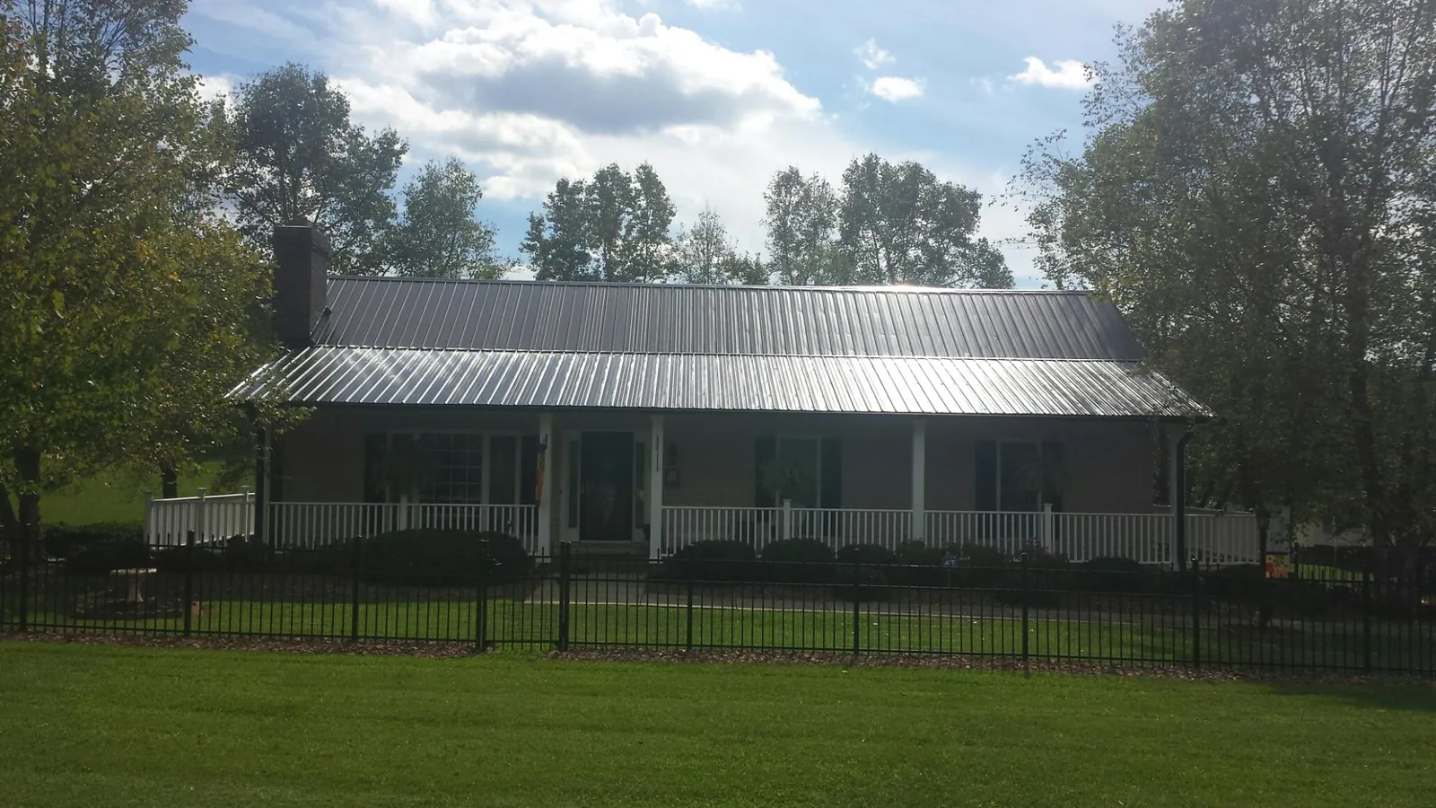 Gray metal roof on a brick ranch with a full width front porch — Gutter Guard Installation work by our crew in Santo Domingo Pueblo