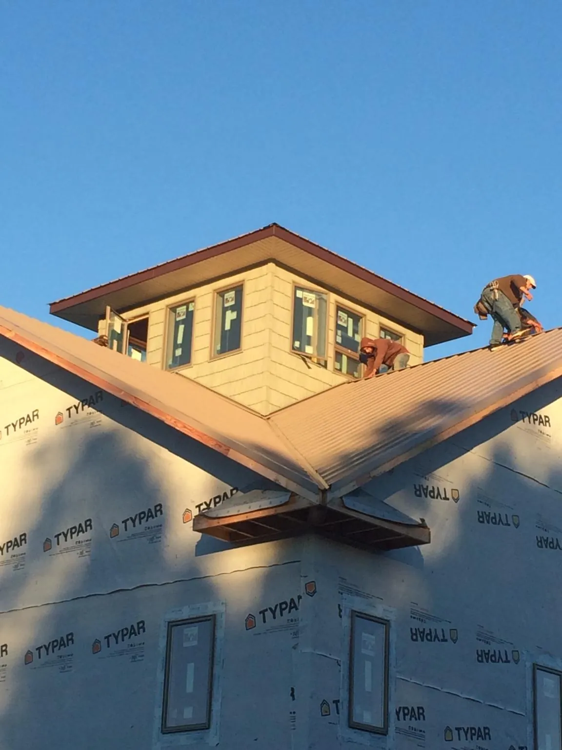 Roofers working around a rooftop cupola on a new metal roof at sunset — Roof Waterproofing in Santo Domingo Pueblo by Roofing Brothers